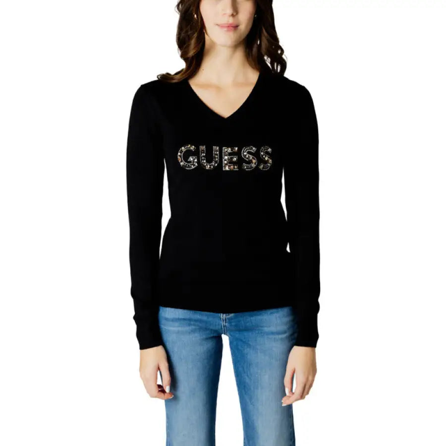 
                      
                        Woman in Guess Women Knitwear black sweater with gold SEI logo
                      
                    