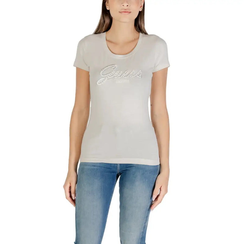 Woman wearing light-colored fitted Guess T-shirt with rhinestone print and blue jeans