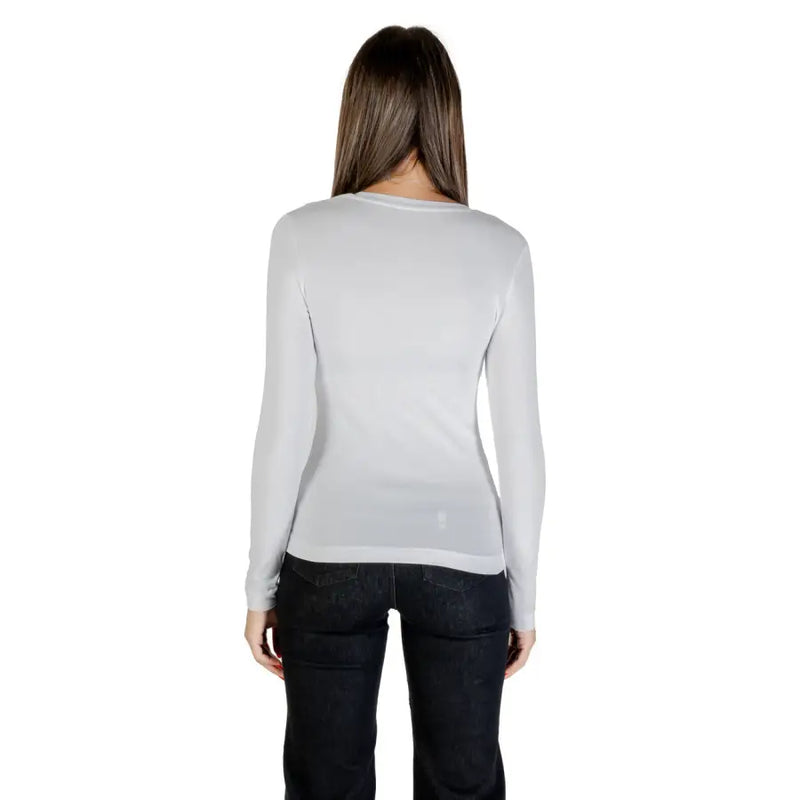 Woman in light grey long-sleeved shirt and dark jeans, back view, Guess Fall Winter T Shirt