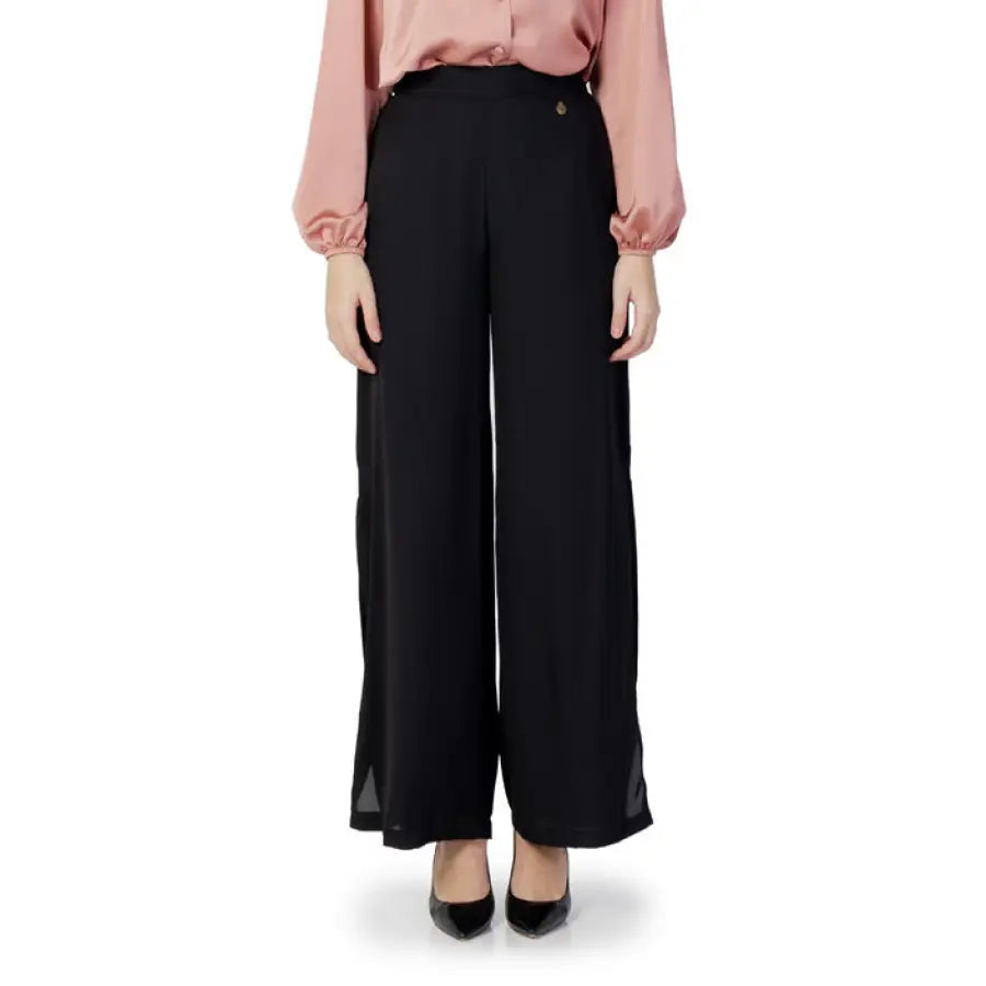 
                      
                        Woman in pink shirt showcasing Akè women trousers for urban style clothing on white background
                      
                    