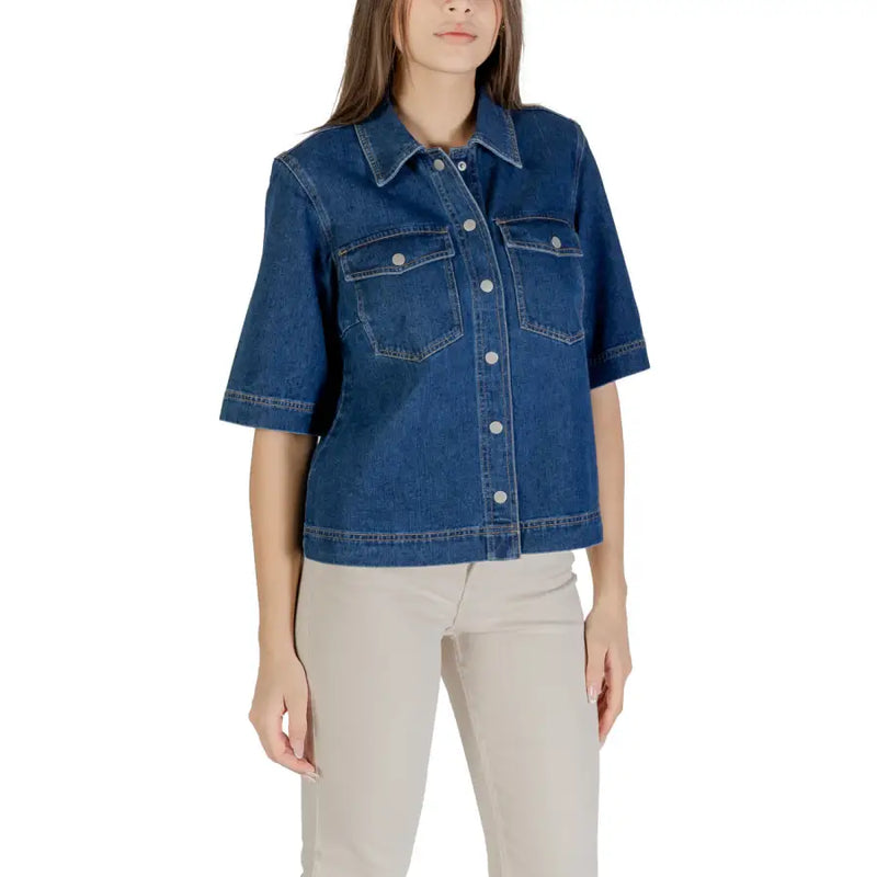 Woman wearing a classic blue short sleeve cotton shirt and light-colored pants