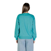 Woman wearing Calvin Klein Jeans teal crewneck sweatshirt and light blue wide-leg pants