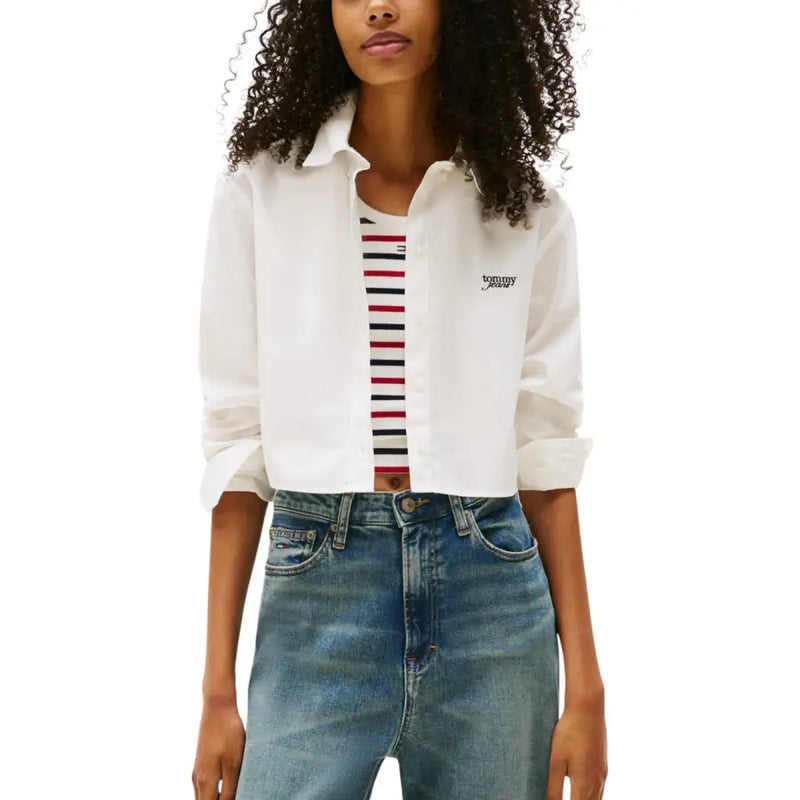 Woman wearing Tommy Hilfiger Jeans white long sleeve button shirt over striped tank top
