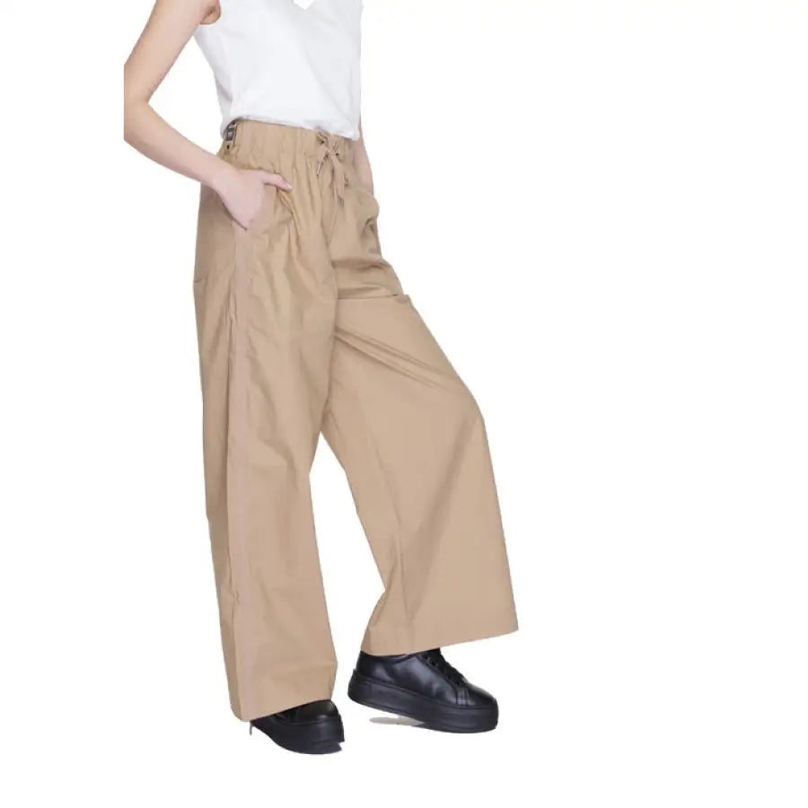 
                      
                        Woman in white shirt, beige Blauer trousers embodying urban city style fashion
                      
                    