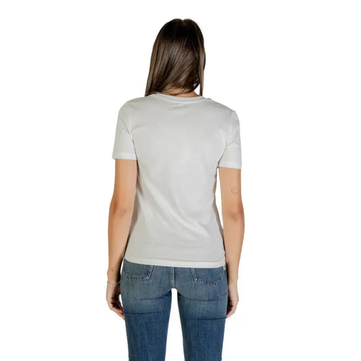 Woman in white short sleeve round neck cotton T shirt and blue jeans viewed from the back