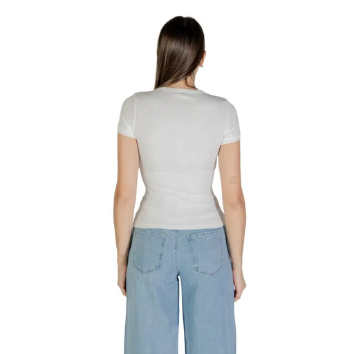 Woman wearing a white short-sleeved T-shirt and light blue wide-leg jeans for Tommy Hilfiger collection