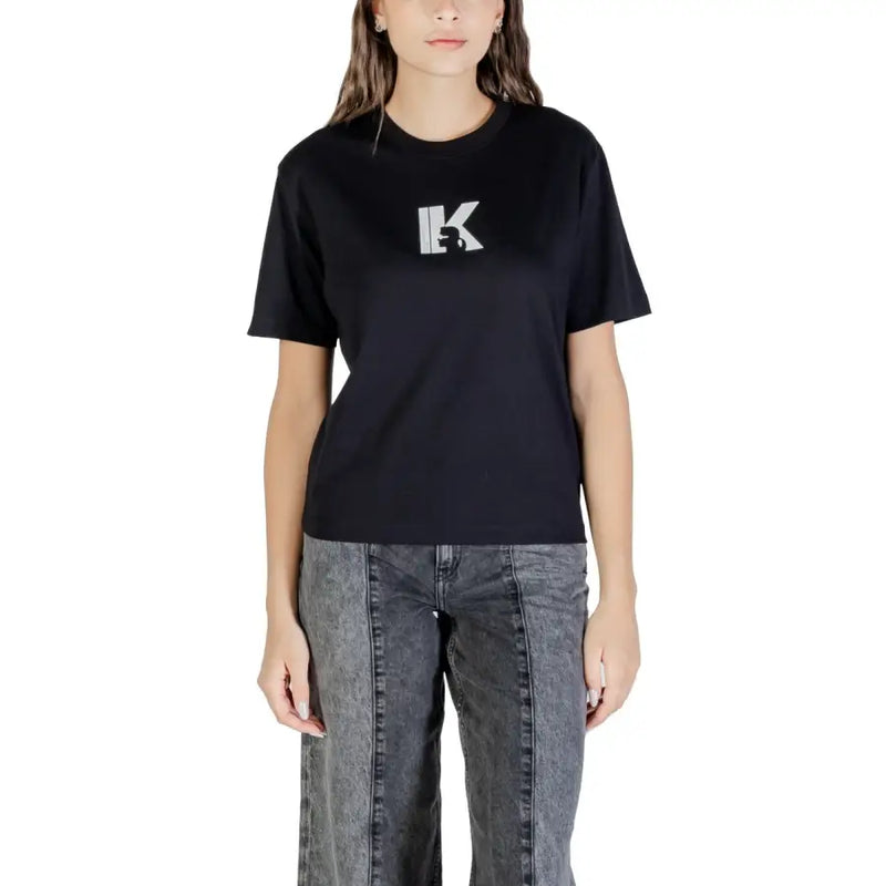 Woman wearing black crew-neck T-shirt with white K graphic and dark wash wide-leg jeans