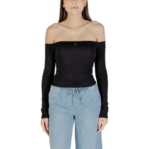 Frau mit schwarzem, schulterfreiem Langarmshirt top mit hellblauen Hosen