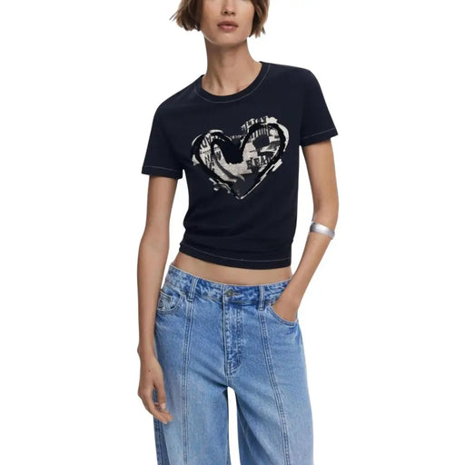 Woman wearing Desigual black print short sleeve round neck T-shirt with white heart graphic and light wash jeans