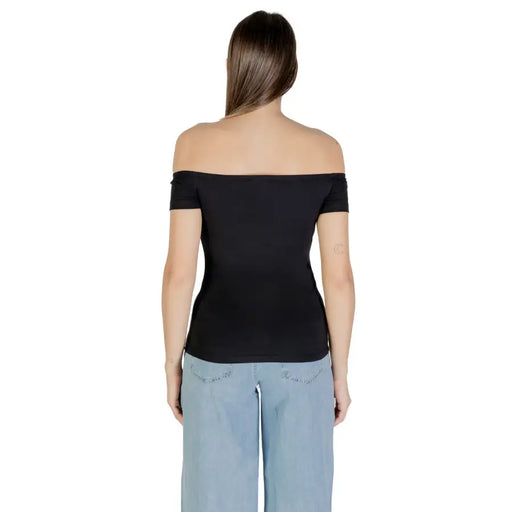 Woman wearing Calvin Klein Jeans black print boat neck top with light blue wide-leg pants