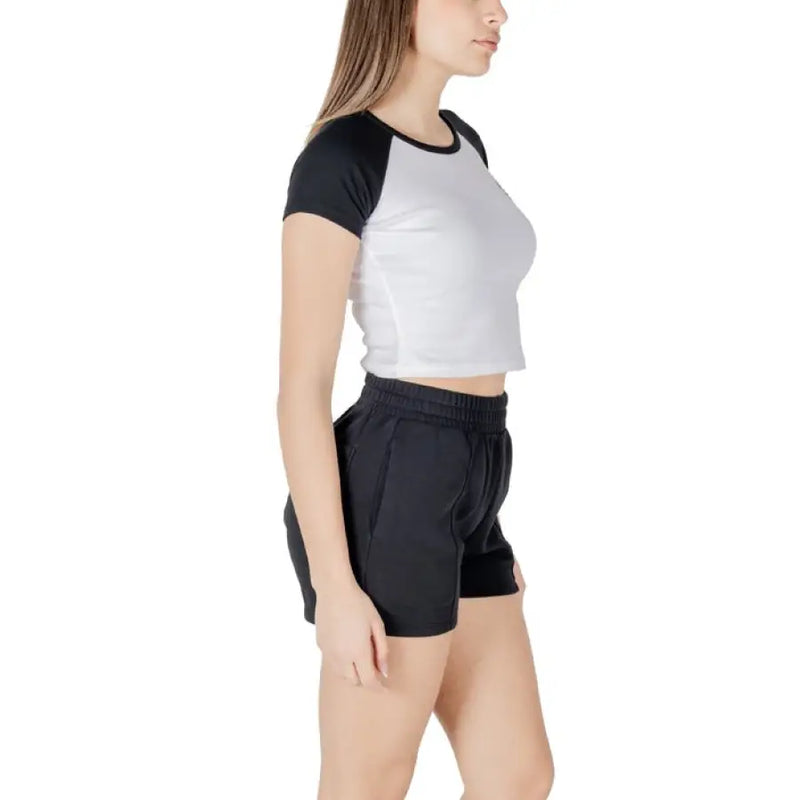 Woman wearing black and white crop top with black shorts showcasing stylish casual outfit