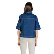 Woman wearing classic blue short sleeve cotton denim shirt with light-colored pants