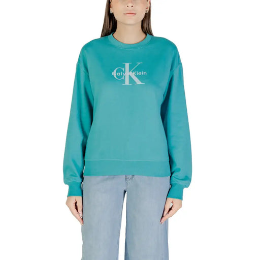 Woman wearing teal Calvin Klein sweatshirt with light blue wide-leg pants for casual style
