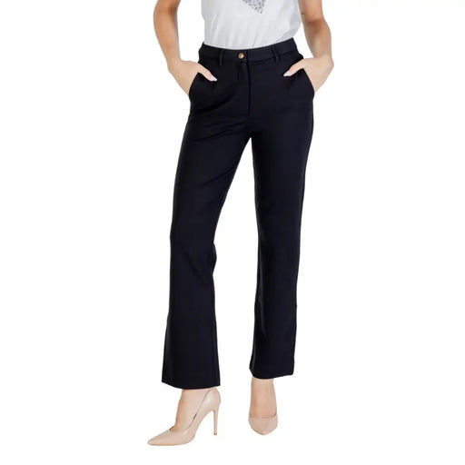Women’s black dress pants with gold button and side pockets paired with nude high heels