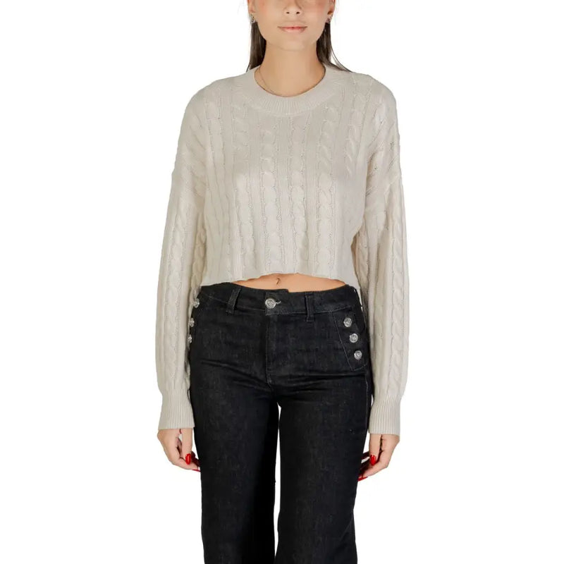 Woman wearing beige cable-knit cropped sweater and dark high-waisted wide-leg jeans for fall winter fashion