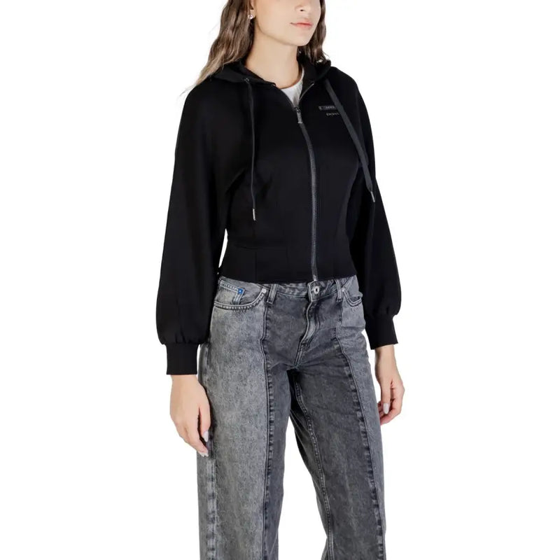 Women’s black zip-up hoodie with drawstring hood and puffed sleeves paired with acid-wash wide-leg jeans