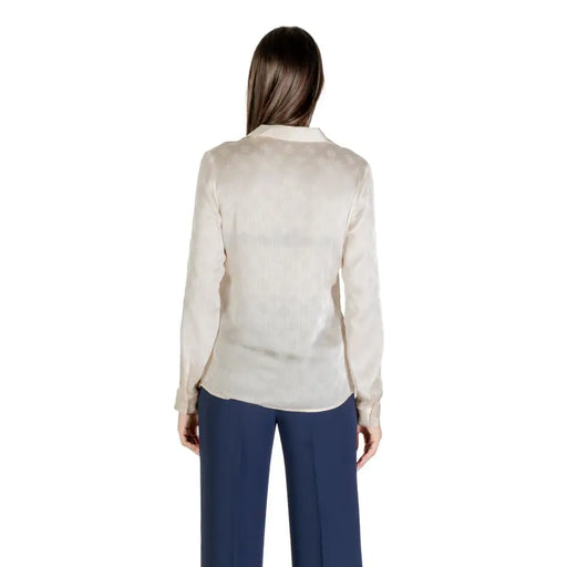Women’s beige long sleeve button-up shirt with round neck paired with dark blue wide-leg pants