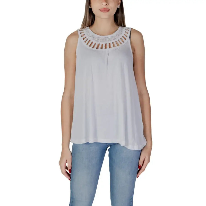 Women’s white sleeveless top with decorative cut-out neckline paired with light blue jeans
